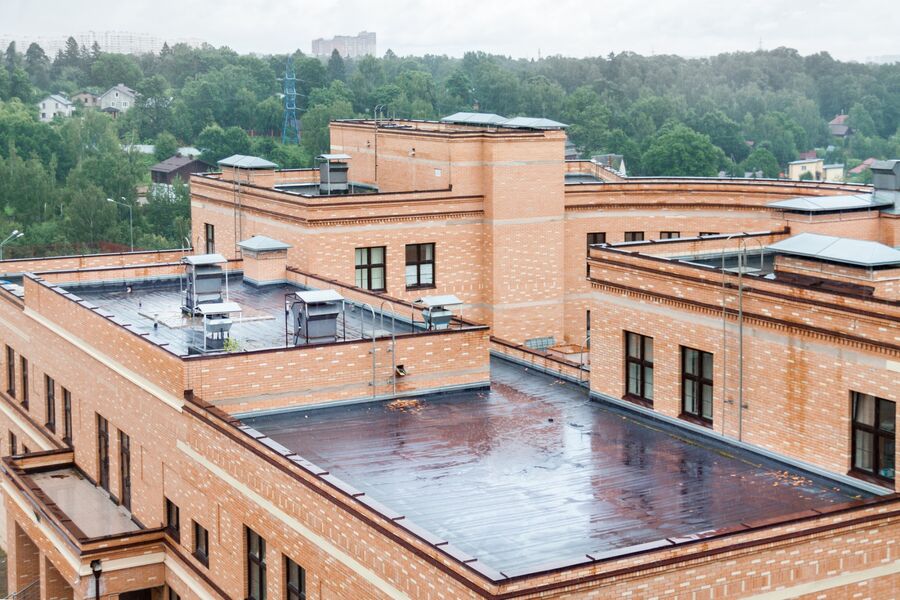 Flat commercial brick building with a newly installed rooftop roofing membrane and vents